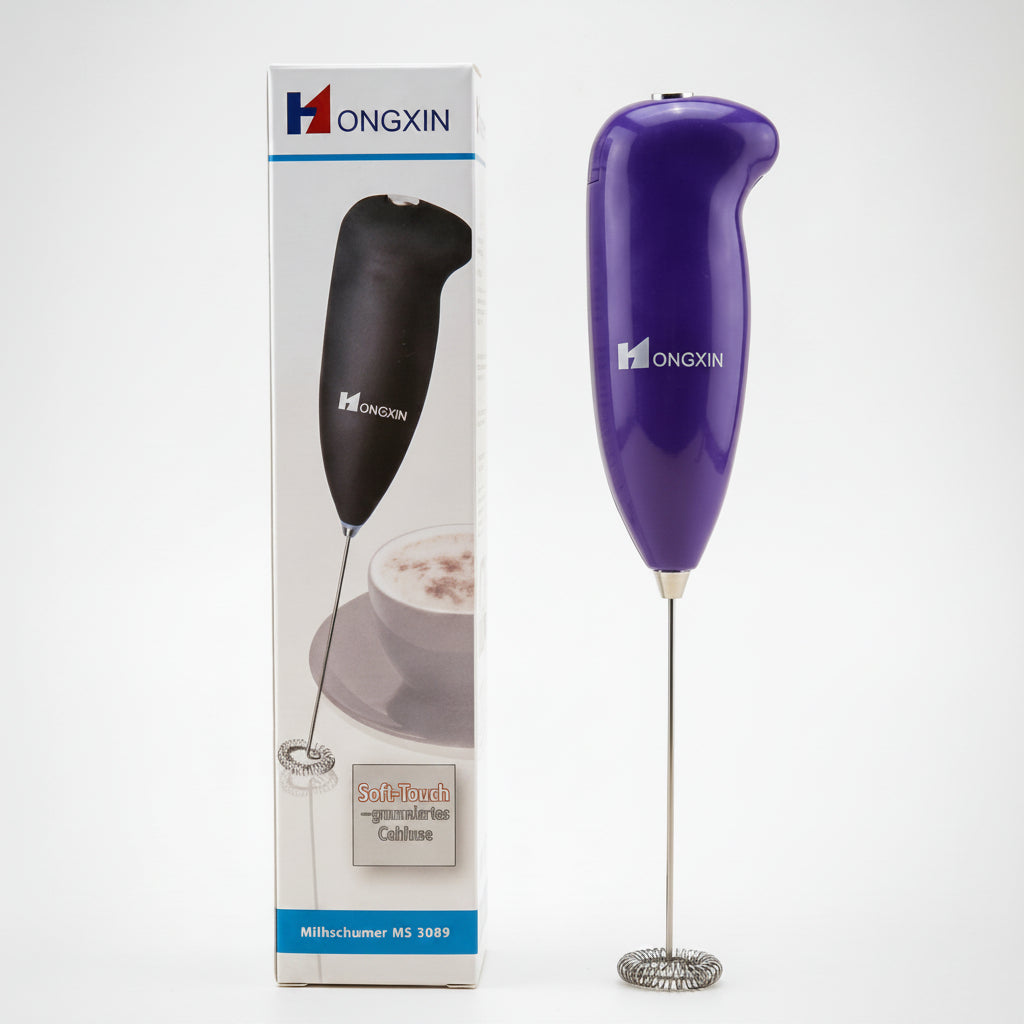 Purple handheld milk frother with packaging on a beige background